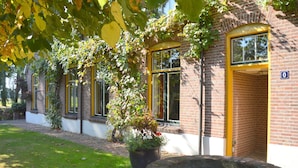 A brick building with yellow-framed windows, a number '0' sign, and a stone well. - Spacious Holiday Home in Rekken With Hot Tub (Rekken)
