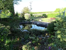 A garden with a pond, surrounded by various plants and a small bridge.