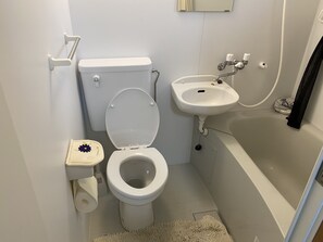 A small bathroom with a toilet, sink, and bathtub. - Beach Lodge 4 & Private Beach (Onna)