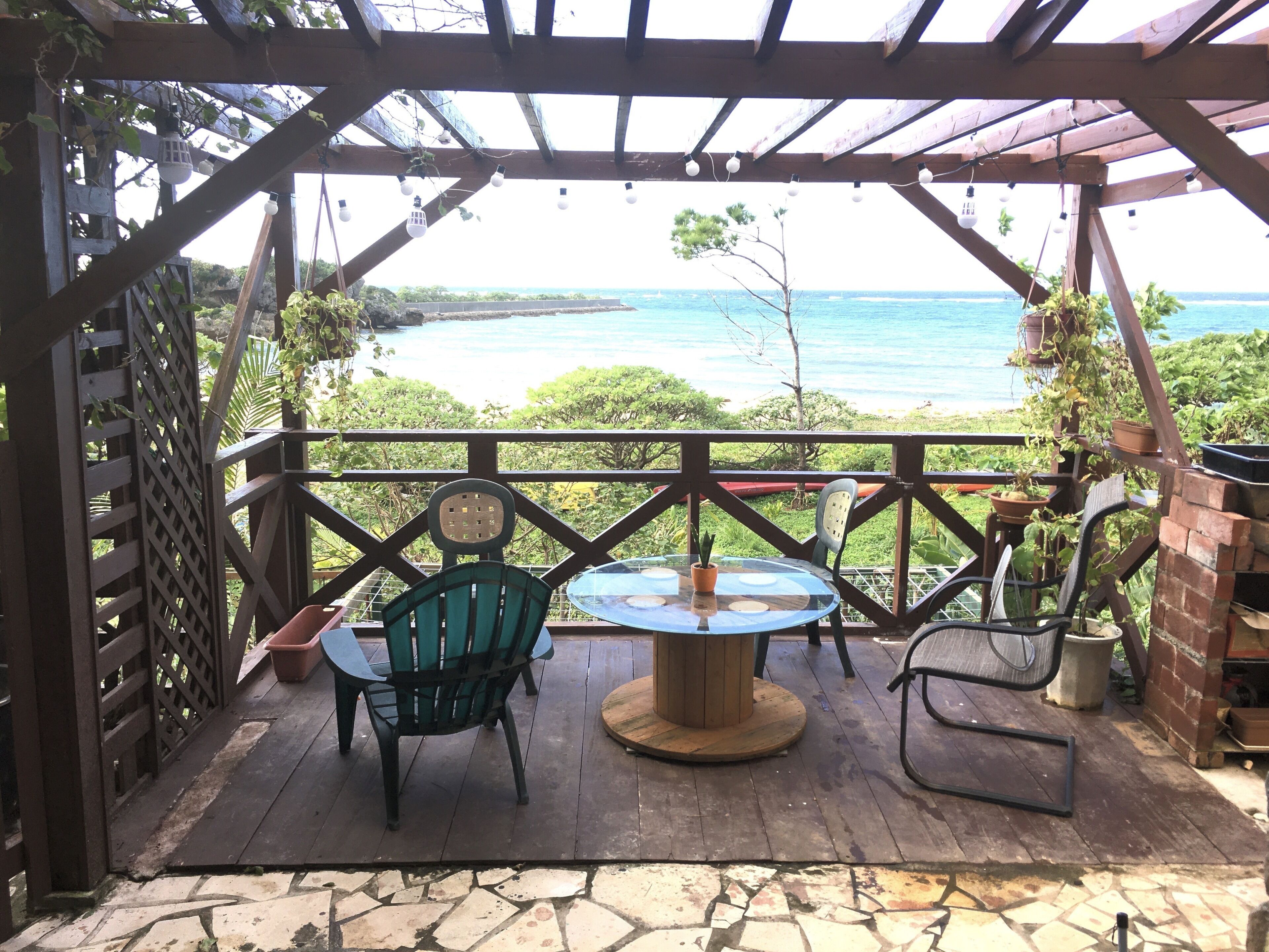 A covered patio with a table and chairs, overlooking a body of water.