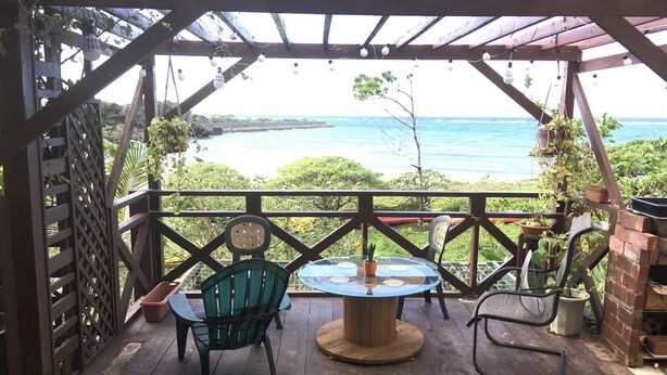 A covered patio with a table and chairs, overlooking a body of water. - Beach House 1 & Private Beach (Onna)