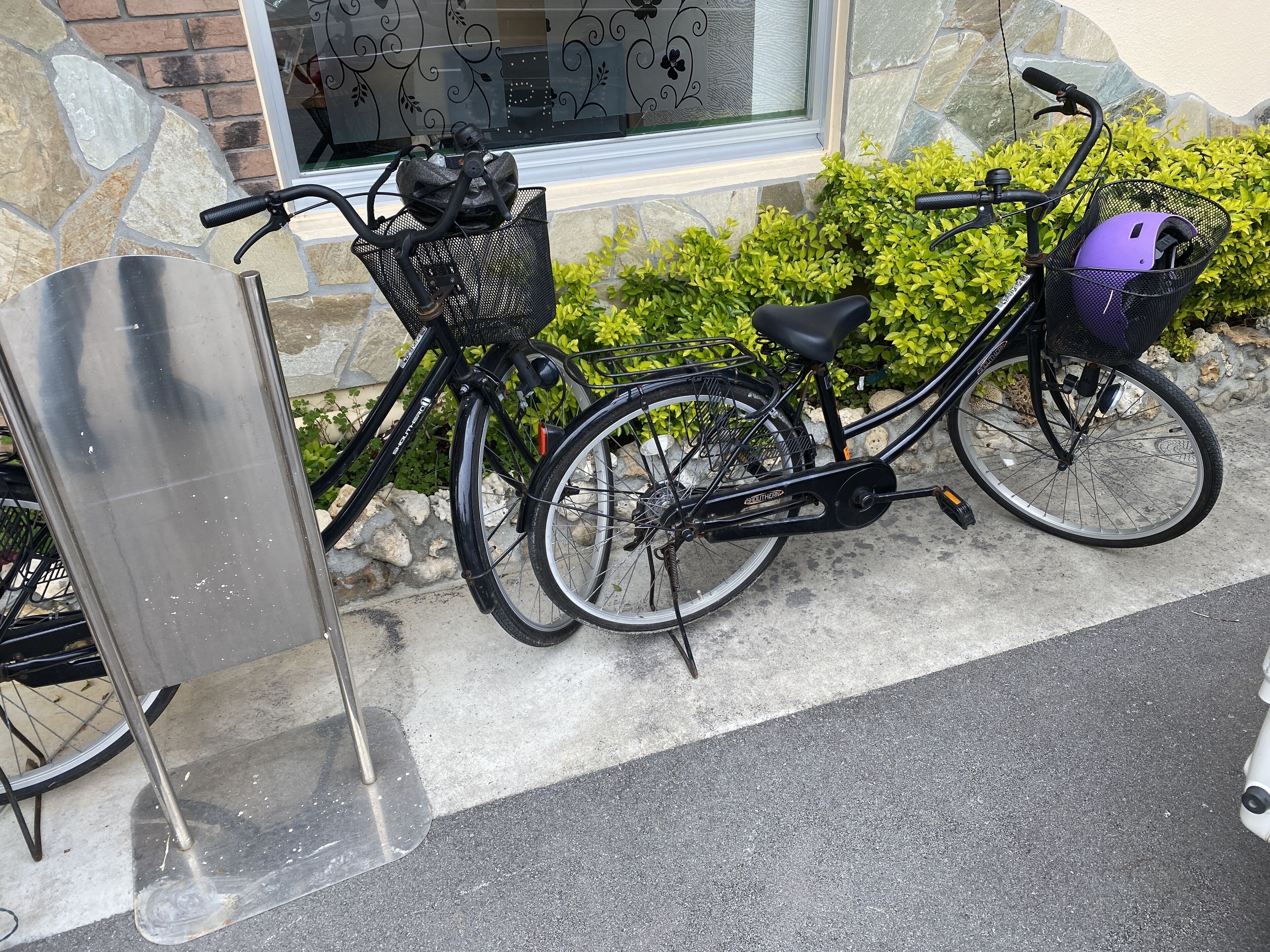 A bicycle parked next to a building with a stone facade and a window with decorative glass.