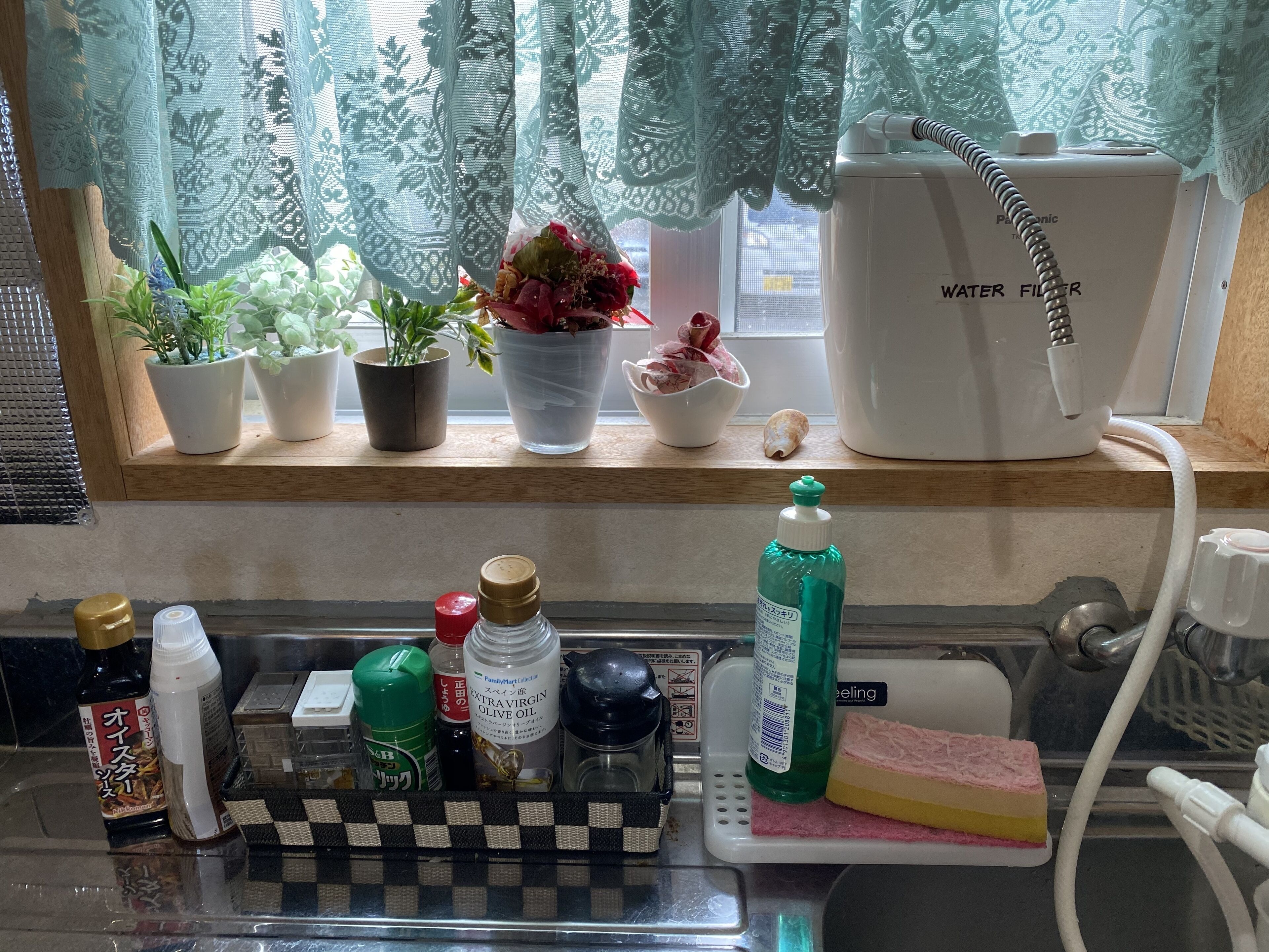 A kitchen counter with various items including a water filter, a bottle of olive oil, and a sponge.