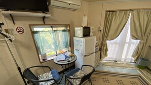 A compact kitchenette with a refrigerator, microwave, and a small table with chairs.