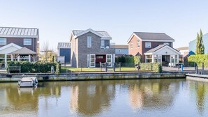 Ett bostadsområde med hus, en kanal och en liten båt som ligger förtöjd vid vattnet.