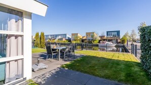 Ett modernt bostadsområde med en uteplats, en kanal och hus i bakgrunden.