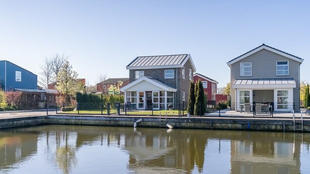 Ett bostadsområde med hus, en damm och en fågel.