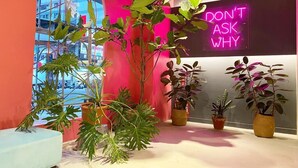 A modern interior with a neon sign, potted plants, and a view through an arched window. - Fengjia Gold Hotel (Taichung)