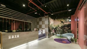 A modern reception area with a checkered wall, a reception desk, and a seating area with a sofa and plants. - Fengjia Gold Hotel (Taichung)