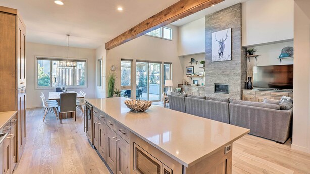 Una cocina amplia con una isla grande, vigas de madera y una pared decorativa de piedra.