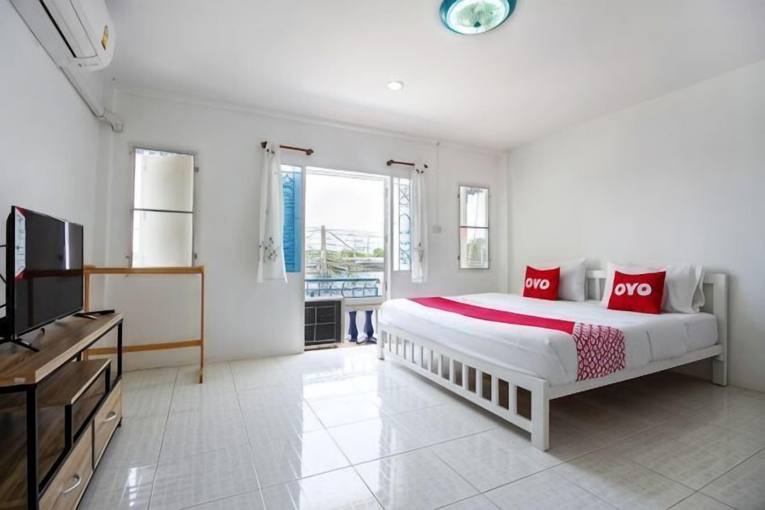 Ein Hotelzimmer mit Bett, Fernseher, Schreibtisch und Balkonblick.