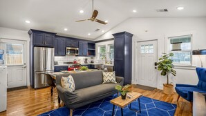 A modern kitchen with dark blue cabinets, stainless steel appliances, and a ceiling fan.
