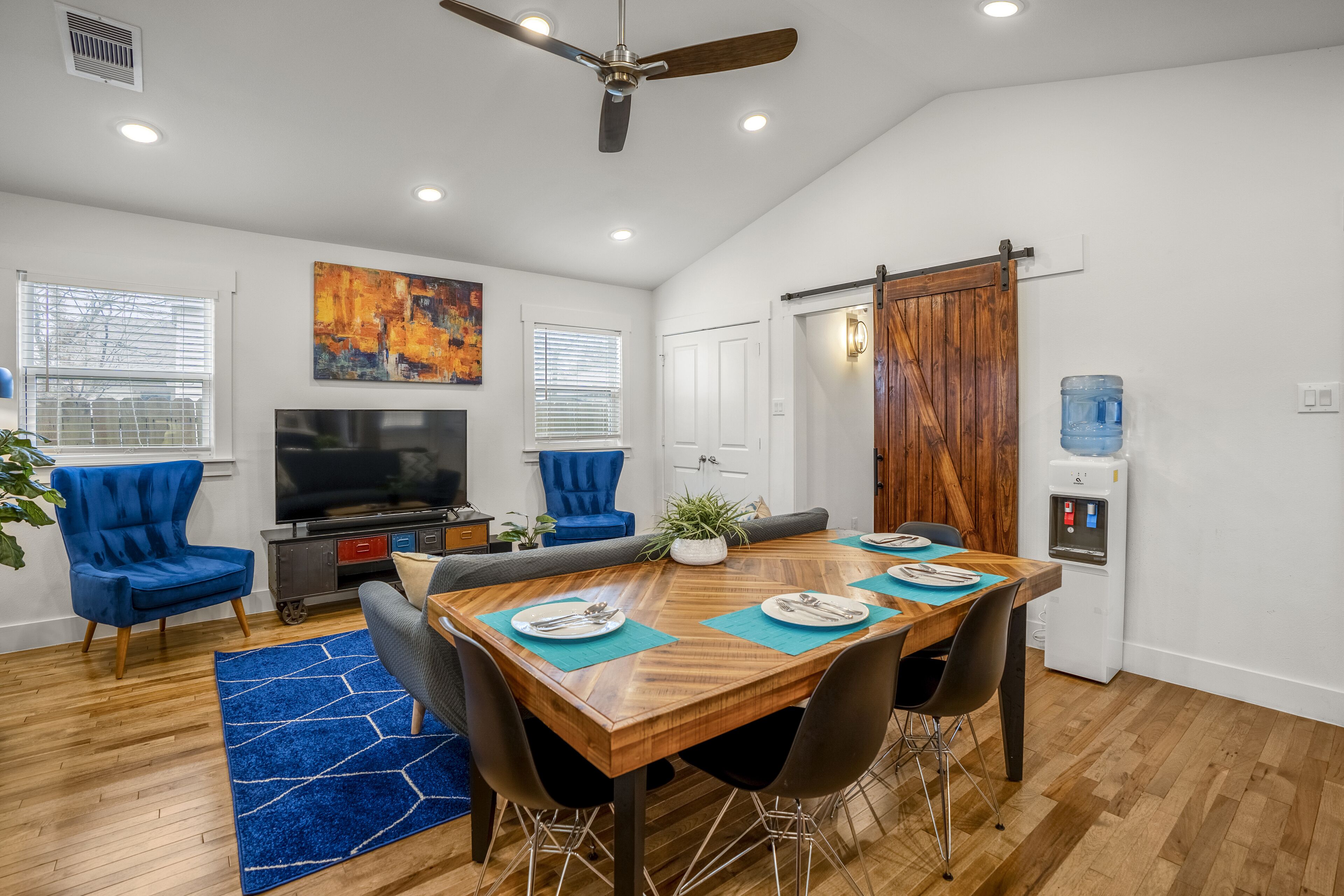 A dining area with a wooden table, blue chairs, and a blue rug.