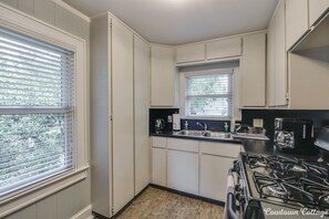 Compact kitchen with gas stove, sink, and coffee maker, offering ample space for meal preparation.