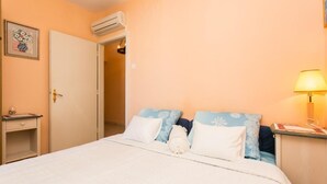 Une chambre à coucher comprenant un lit, une table de chevet, une lampe et un appareil de climatisation.