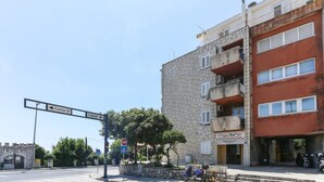 Une vue de rue avec un panneau de signalisation indiquant un arrêt obligatoire, un passage piéton et un bâtiment sur lequel on peut lire l’inscription « Regina ‘Mad’ ».