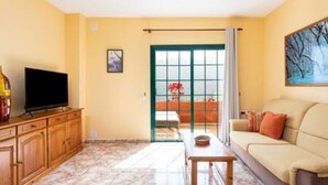 Una sala de estar con sofá, televisor y una mesa.