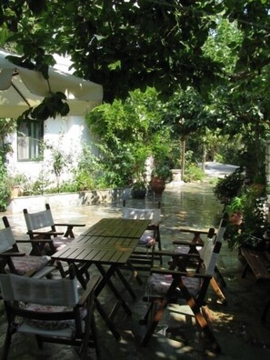 Un patio al aire libre con una mesa y sillas, rodeado de vegetación exuberante y plantas en macetas.