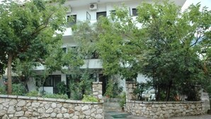 A building with a stone wall, greenery, and a staircase leading to an upper level. - Yasemi Rooms (Lefkada)