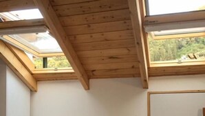 A bedroom with a bed, a nightstand, and skylights. - Yasemi Rooms (Lefkada)