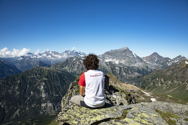 A person sitting on a rock with a mountainous landscape in the background. - Albergo Ristorante Cuccini (Varzo)