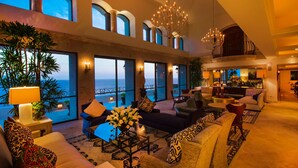 A spacious living area with large windows overlooking the ocean, furnished with sofas and a coffee table, and featuring a chandelier and potted plants. - Exclusive Holiday Villa with Private Pool near Beach, Cabo San Lucas Villa 1042 (Cabo San Lucas)