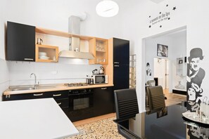 Une cuisine moderne avec des meubles noirs, un four à micro-ondes et une cuisinière. On y trouve également un coin repas avec une table et des chaises blanches.