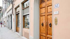 A street with a row of shops, a wooden door with a brass knocker, and a sign with the number 87. - GuestHost - Located in the heart of the city, near the places of greatest cultural interest and a few steps from the Santa Maria Novella station, it is the ideal place for tourist or business stays.The area of ​​Borgo Ognissanti reflects the ancient  (Florence)