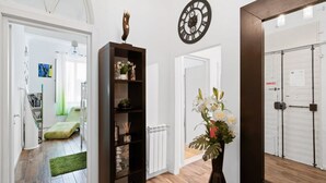 A hallway with a wooden floor, a black bookshelf, a white radiator, and a wall clock. - GuestHost - Located in the heart of the city, near the places of greatest cultural interest and a few steps from the Santa Maria Novella station, it is the ideal place for tourist or business stays.The area of ​​Borgo Ognissanti reflects the ancient  (Florence)