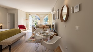 A modern living room with a dining area, a red chair, a sofa, and a large mirror on the wall.