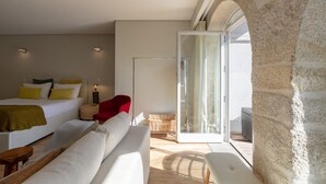 A modern bedroom with a bed, a red chair, a sofa, and a glass door leading to an outdoor area.
