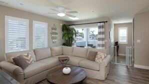 A living room with a sectional sofa, a round coffee table, and a ceiling fan. - Beautiful Updated House with Ocean Views in Downtown Pismo (Pismo Beach)