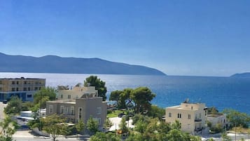 Una zona residenziale costiera con edifici moderni, vista limpida sul mare e montagne in lontananza.