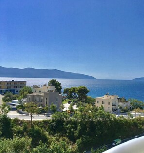 Una zona residencial costera con edificios modernos, vista despejada al mar y montañas a lo lejos.