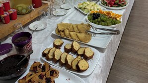Un buffet proposant une variété de plats et de boissons, notamment des fruits, des pâtisseries et une tarte.