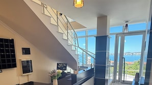 Une cuisine moderne dotée d’un îlot central aux lignes courbes, d’un escalier et offrant une vue sur la mer.