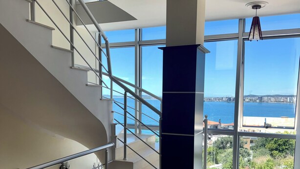 Un intérieur moderne avec un escalier, de grandes fenêtres et une vue sur la mer.