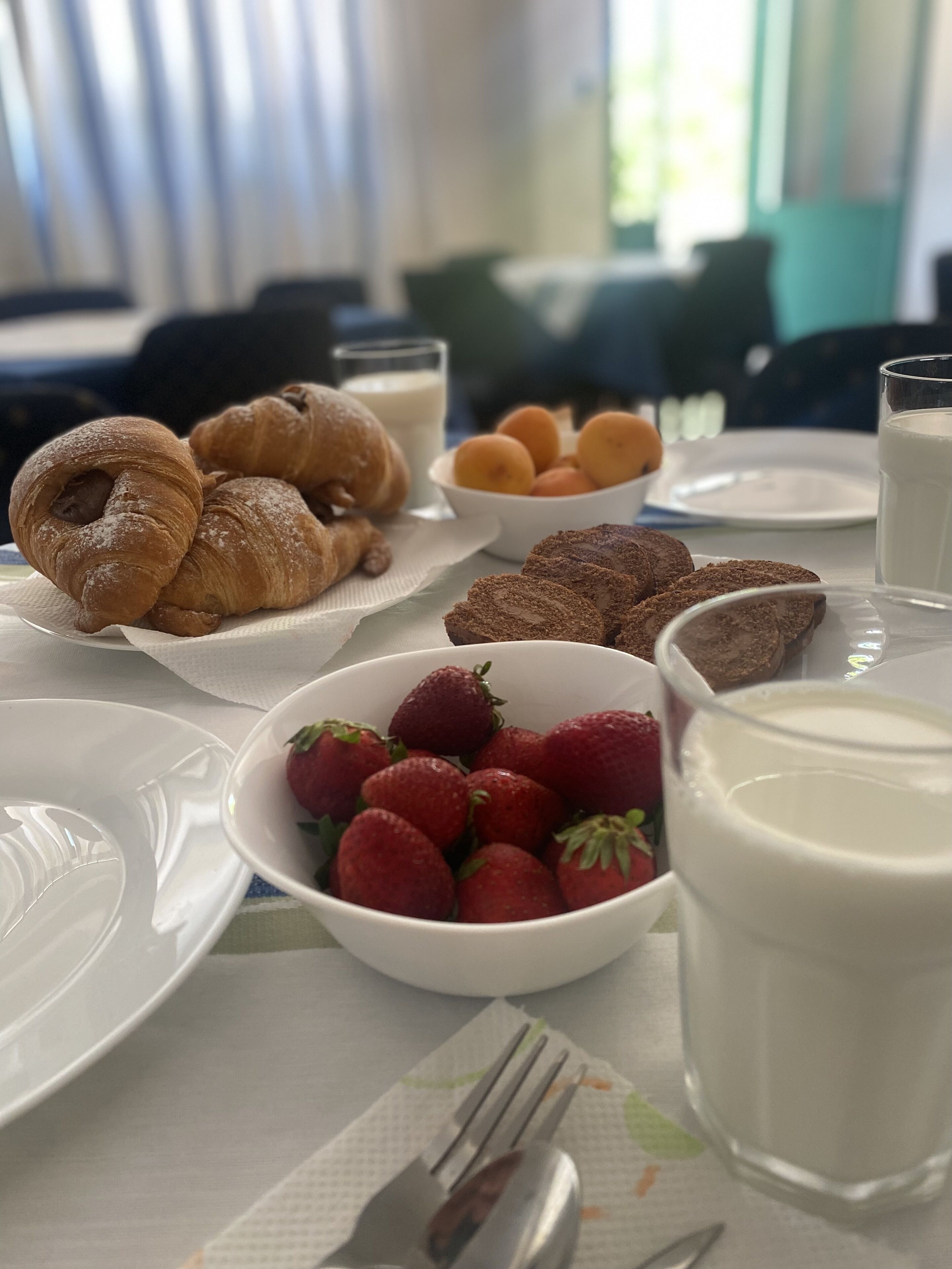Ett frukostbord med croissanter, jordgubbar och mjölk.