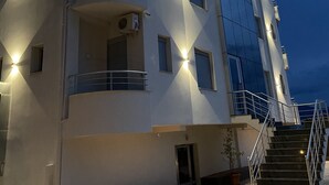 Un immeuble à plusieurs étages doté de balcons, d’un escalier et d’un éclairage extérieur.