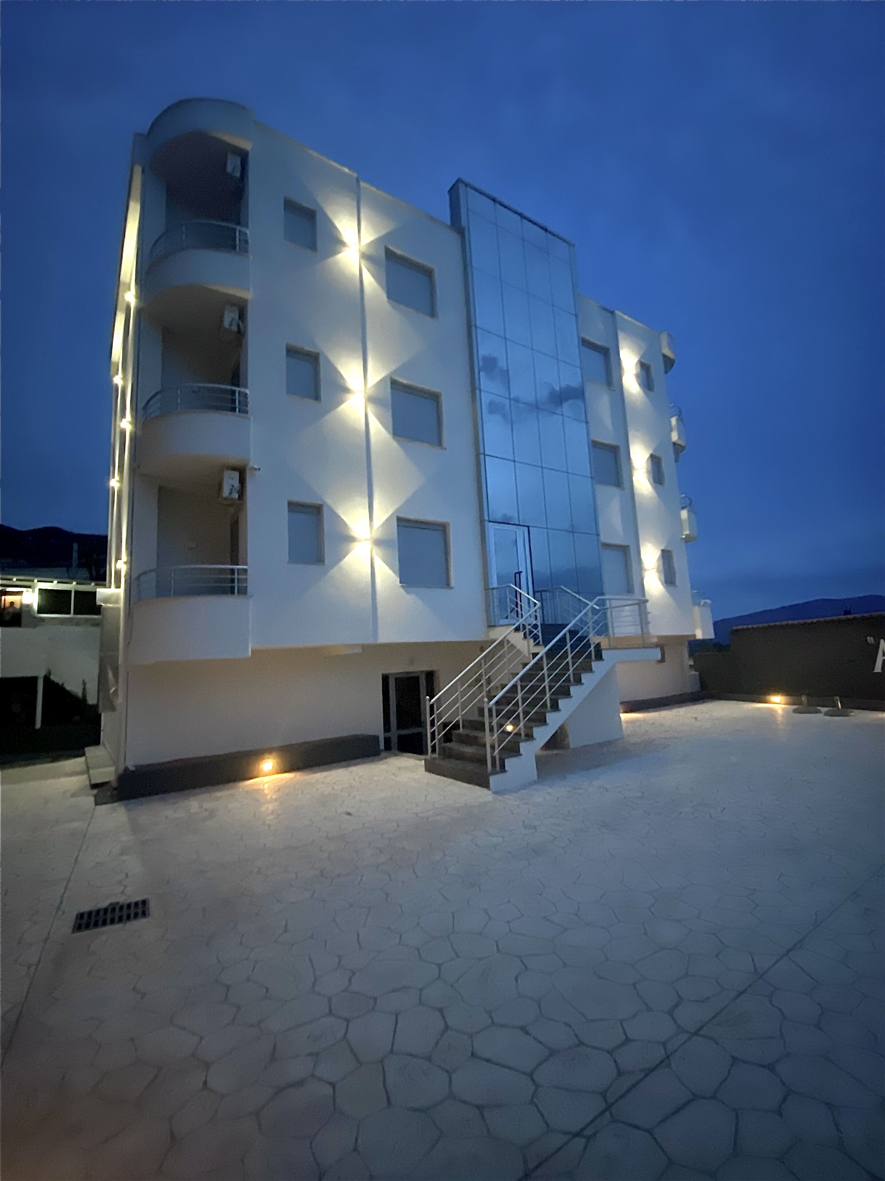 Een modern gebouw met een gebogen gevel, meerdere balkons en een centrale trap.