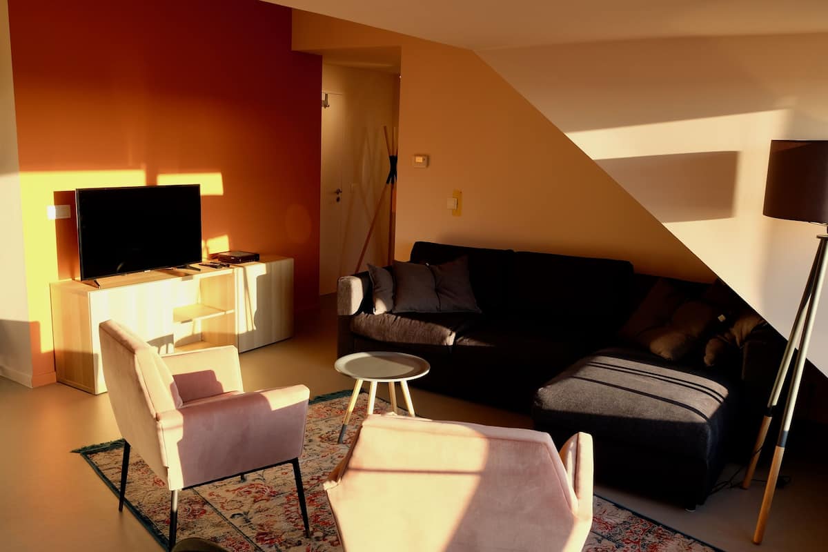 A living room with a sofa, armchairs, a coffee table, a flat-screen TV, and a lamp.