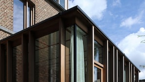 A modern building with large glass windows and a brick facade. - Le Presbytère (Engis)