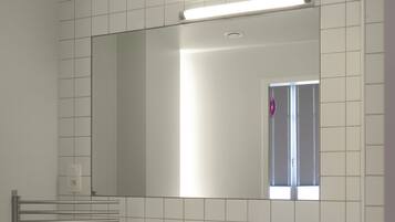 A modern bathroom with a white sink, mirror, and tiled walls.