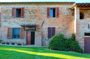 A rustic two-story building with a stone facade, wooden shutters, and a small front porch. - Villa Alessandro (Citta della Pieve)