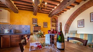 A dining area with a wooden table, a bottle of champagne, and a menu. - Villa Alessandro (Citta della Pieve)