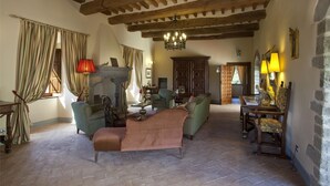 A traditional living room with exposed wooden beams, a fireplace, and classic furniture. - Castello Degli Arcieri (Gubbio)