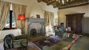 A cozy living room with a fireplace, wooden beams, and a chandelier. - Castello Degli Arcieri (Gubbio)