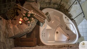 Una bañera de piedra con un banco de madera, velas y un ramo de rosas.