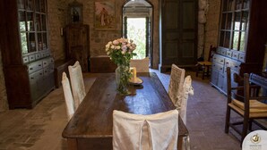 Un comedor rústico con una mesa de madera, sillas tapizadas en blanco y un jarrón de flores.