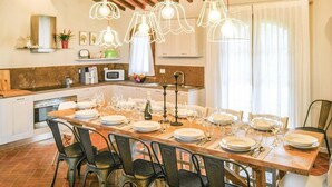 Uma área de refeições com uma mesa comprida posta para uma refeição, rodeada por cadeiras.